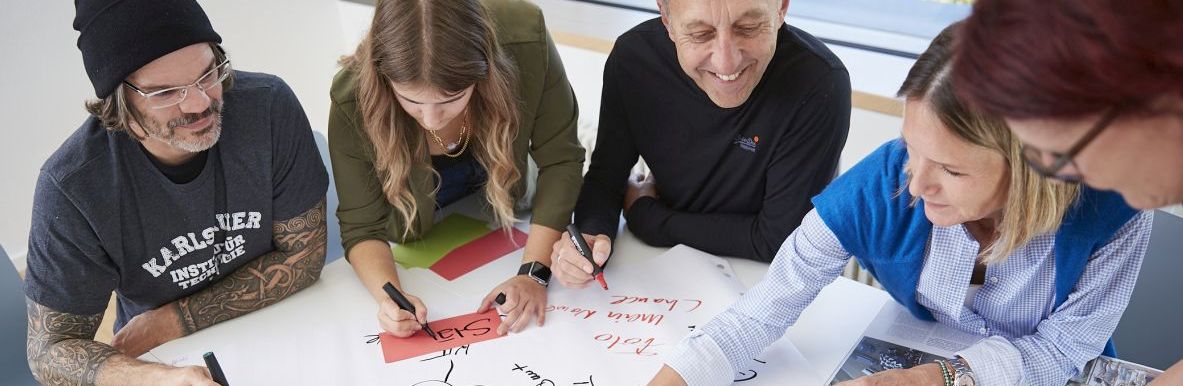 KIT Gruppe von Personen arbeitet gemeinsam an einem großen Whiteboard-Tisch.